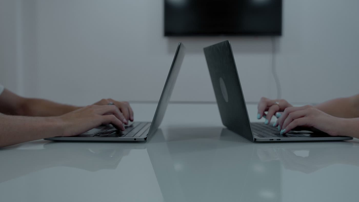 Zwei Personen arbeiten nebeneinander an Laptops